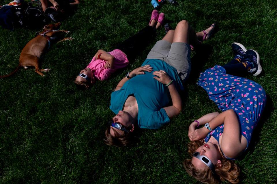 From left, Graeme, 7, Janet, and Ellis Sheaves, 10, wear protective glasses while viewing the solar eclipse during a watch party at the Morehead Planetarium and Science Center at UNC-Chapel Hill on Monday, April 8, 2024.