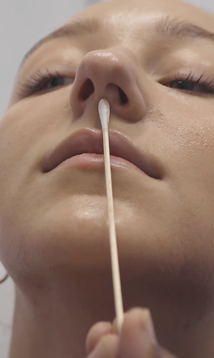 A closeup of someone taking a nose swab of Ava