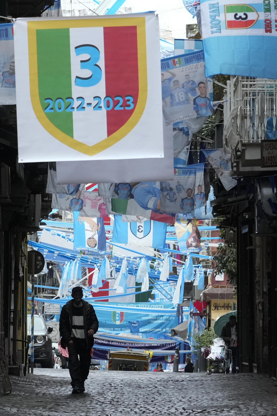 A man walks in a street adorned with Napoli soccer team flags in Naples, Italy, Monday, May 1, 2023. Napoli wasted what seemed like a perfect chance to seal the Serie A title, at home inside the Stadio Diego Armando Maradona on a holiday weekend afternoon in a 1-1 draw with regional rival Salernitana on Sunday. The result disappointed legions of Napoli fans who had already started celebrating in anticipation of the championship. (AP Photo/Gregorio Borgia)