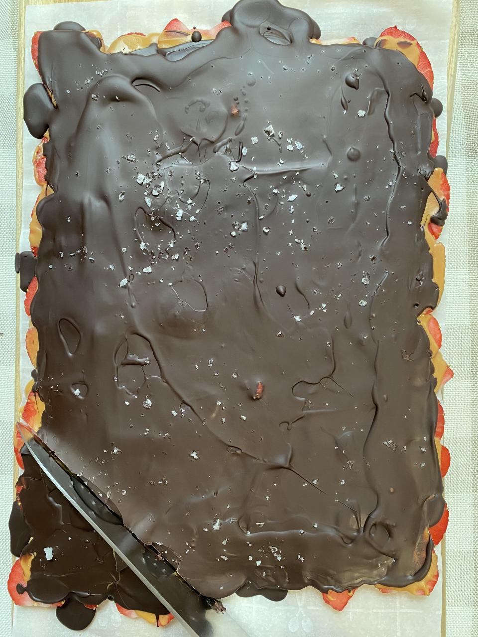 A knife slicing into a frozen strawberry chocolate bark