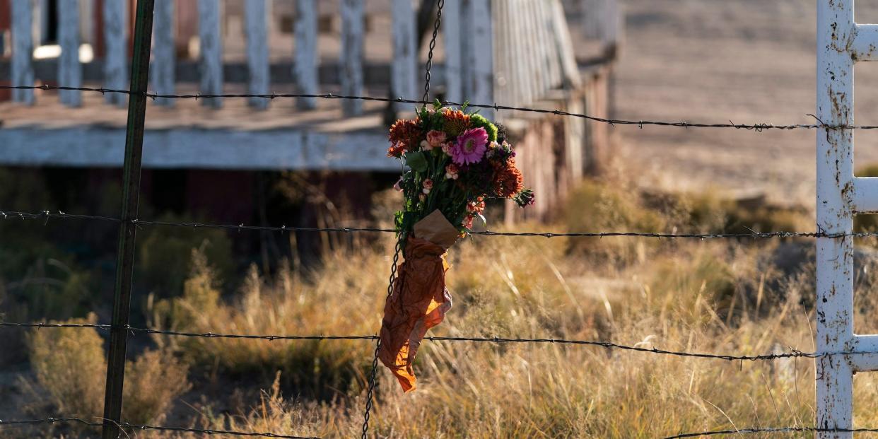 A bouquet of flowers attached to a wire fence in warm sunlight, in tribute to the shooting of Halyna Hutchins on the set of "Rust"