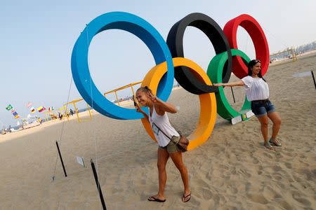 Women pose in front of Olympic rings on Copacabana Beach in Rio de Janeiro, less than two weeks before the start of the Rio 2016 Olympic Games, July 25, 2016. REUTERS/Kai Pfaffenbach