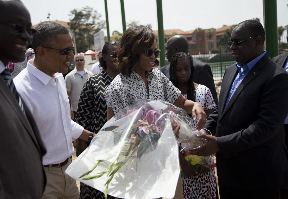 President Barack Obama and first lady Michelle Obama receive flowers after arriving for a tour of Goree Island, Thursday, June 27, 2013, in Goree Island, Senegal. Goree Island is the site of the former slave house and embarkation point built by the Dutch in 1776, from which slaves were brought to the Americas. (AP Photo/Evan Vucci)