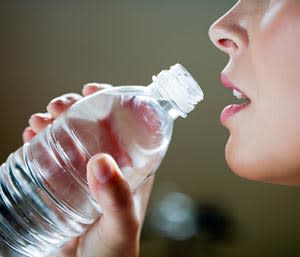 4 Surprising Secrets About Bottled Water // woman drinking out of a water bottle © Thinkstock