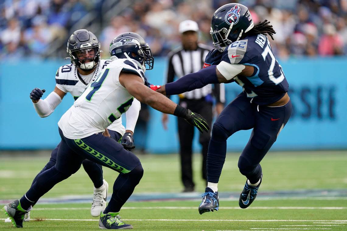 Tennessee Titans running back Derrick Henry, right, runs against Seattle Seahawks linebacker Bobby Wagner, middle, and safety Julian Love (20) during the second half of an NFL football game on Sunday, Dec. 24, 2023, in Nashville, Tenn. (AP Photo/George Walker IV)