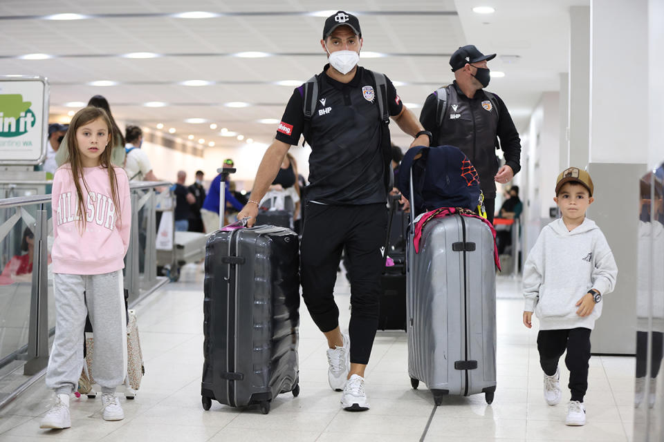 Man and two children walking through airport with luggage