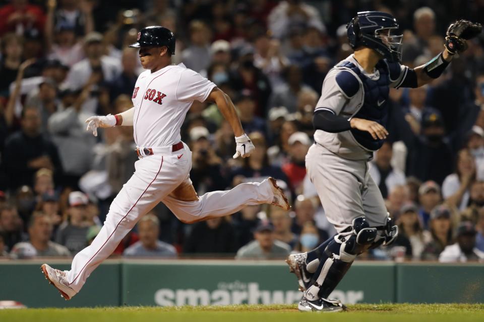 Boston Red Sox's Rafael Devers, left, scores past New York Yankees' Gary Sanchez on a sacrifice fly by J.D. Martinez during the fourth inning of a baseball game, Sunday, Sept. 26, 2021, in Boston. (AP Photo/Michael Dwyer)