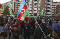 People wave Azerbaijan national flags during a funeral ceremony of a member of the Azerbaijani Armed Forces who was allegedly killed during fighting over the breakaway region of Nagorno-Karabakh in Tartar region, Azerbaijan, Wednesday, Sept. 30, 2020. Leaders of Azerbaijan and Armenia brushed off the suggestion of peace talks Tuesday, accusing each other of obstructing negotiations over the separatist territory of Nagorno-Karabakh, with dozens killed and injured in three days of heavy fighting. (AP Photo/Aziz Karimov)