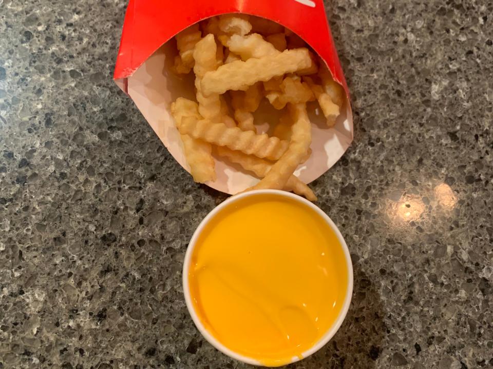 portillos french fries next to a cup of cheese sauce