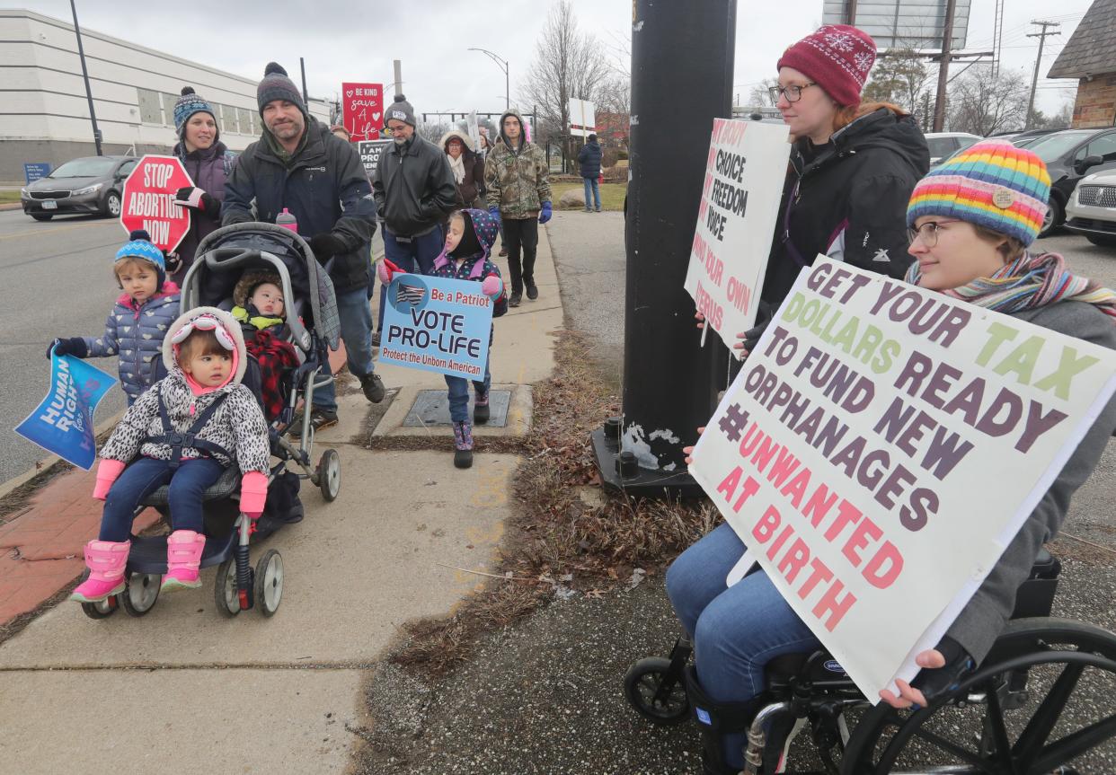 Anti-abortion marchers pass abortion-rights protesters in front of the Northeast Ohio Women's Center in Cuyahoga Falls on Saturday.