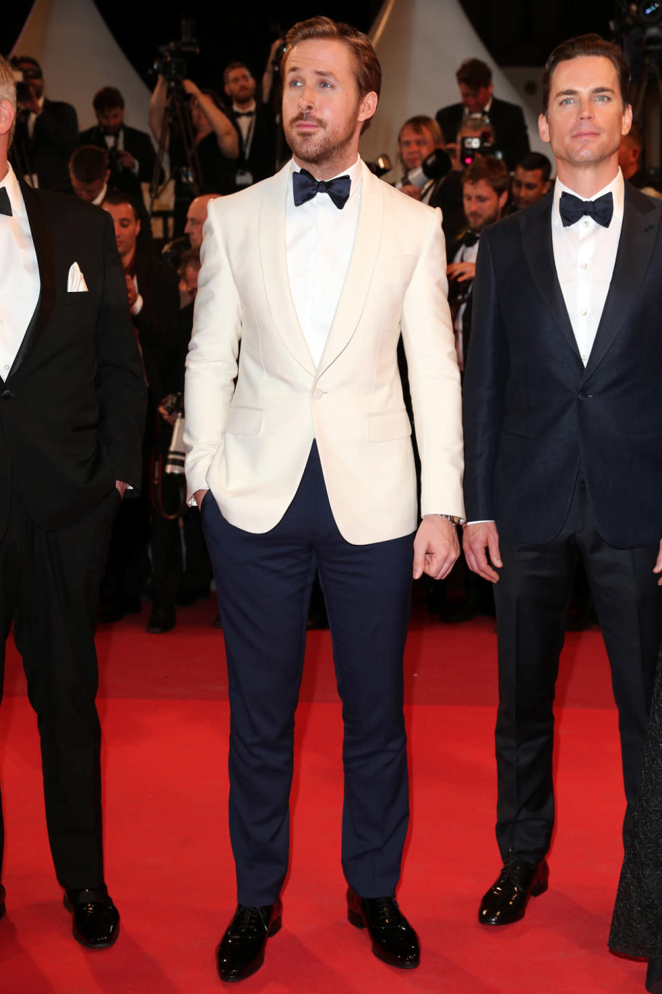 Ryan Gosling in navy blue trousers with a matching bowtie and white tuxedo jacket 