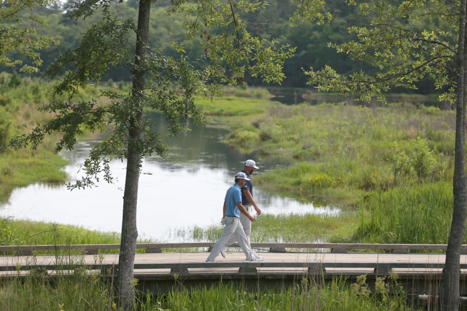 Dustin Johnson and Kevin Kisner walk across a bridge from the second tee during the first round of the Palmetto Championship at Congaree in June 2021.