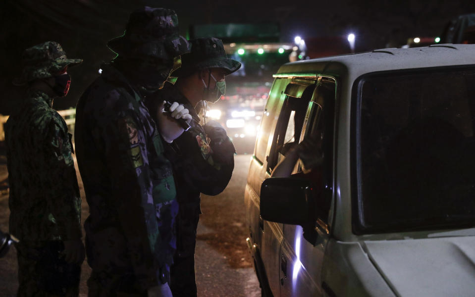 Policemen inspect vehicles at a checkpoint in Quezon city, metropolitan Manila, Philippines early Sunday March 15, 2020. Thousands of Philippine police, backed by the army and coast guard, have started sealing the densely populated capital from most domestic travelers in one of Southeast Asia's most drastic containment moves against the coronavirus. For most people, the new coronavirus causes only mild or moderate symptoms. For some, it can cause more severe illness, especially in older adults and people with existing health problems. (AP Photo/Aaron Favila)