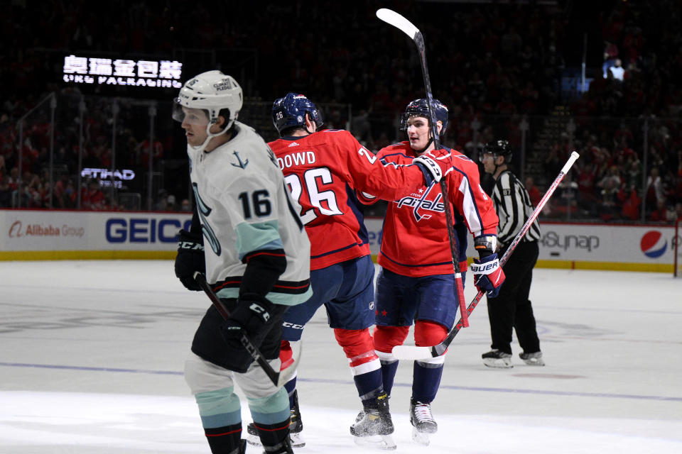 Washington Capitals defenseman Dmitry Orlov (9) celebrates his goal with center Nic Dowd (26) as Seattle Kraken left wing Jared McCann (16) skates by during the first period of an NHL hockey game, Saturday, March 5, 2022, in Washington. (AP Photo/Nick Wass)