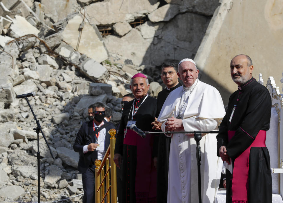 Pope Francis, surrounded by shells of destroyed churches, attends a prayer for the victims of war with Mosul and Aqra Archbishop Najib Mikhael Moussa, left, at Hosh al-Bieaa Church Square, in Mosul, Iraq, once the de-facto capital of IS, Sunday, March 7, 2021. The long 2014-2017 war to drive IS out left ransacked homes and charred or pulverized buildings around the north of Iraq, all sites Francis visited on Sunday. (AP Photo/Andrew Medichini)