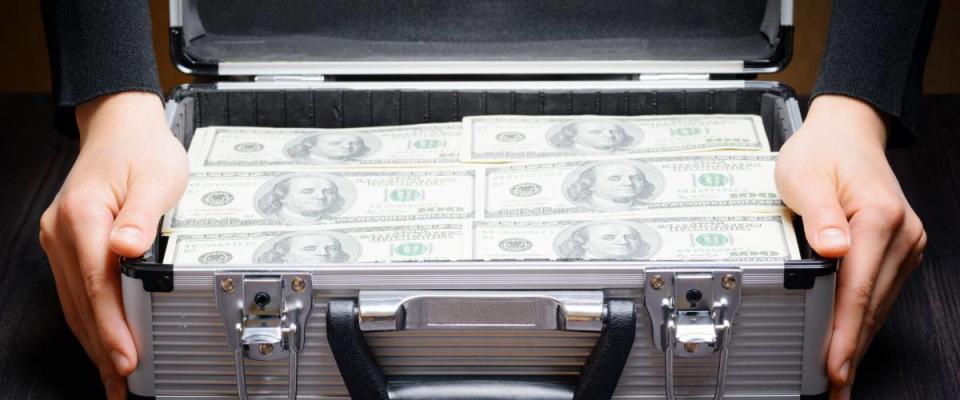 Storage and protection of cash and valuable items. Banking concept. Business man opens an aluminum briefcase full of stacks of hundred dollar bills. Money in safe hands.
