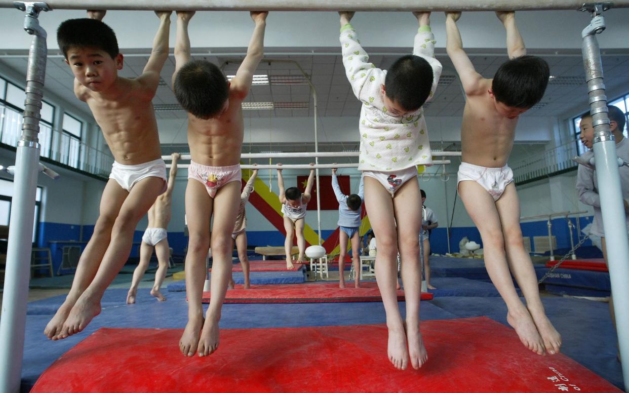 Boys stretch during a school gymnastics training session in Beijing  - FREDERIC J. BROWN /AFP