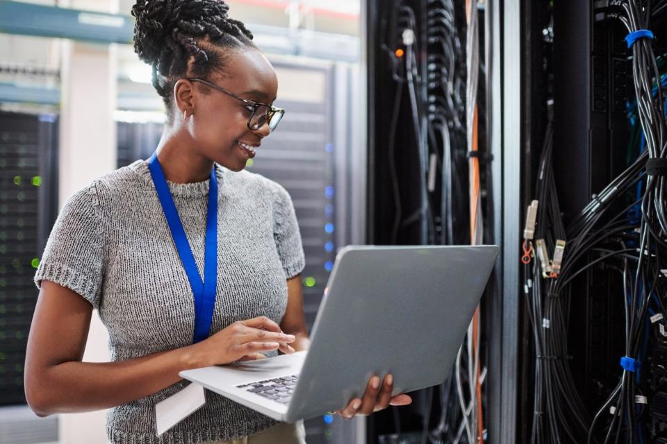 A person on a laptop in a data center.