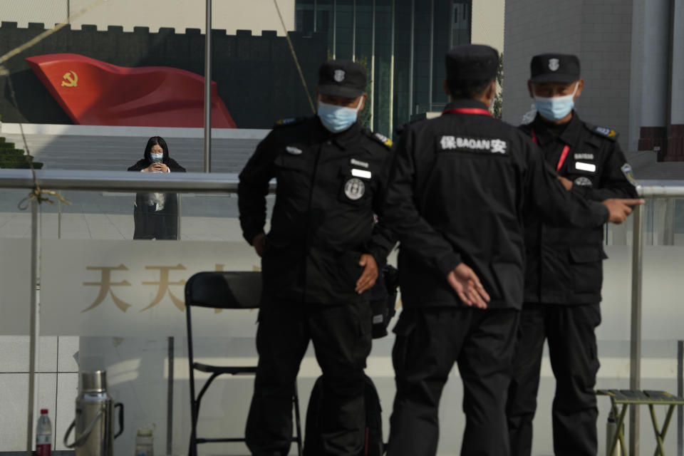 A visitor to the Museum of the Communist Party of China checks her phone near security guards wearing masks in Beijing, Wednesday, Oct. 12, 2022. For decades Chinese journalist Ho Pin has successfully predicted rising newcomers in the Chinese Communist Party, and says that leader Xi Jinping is so powerful, there is little point in predicting the leadership line up to be announced at the Communist Party congress that begins Sunday. (AP Photo/Ng Han Guan)