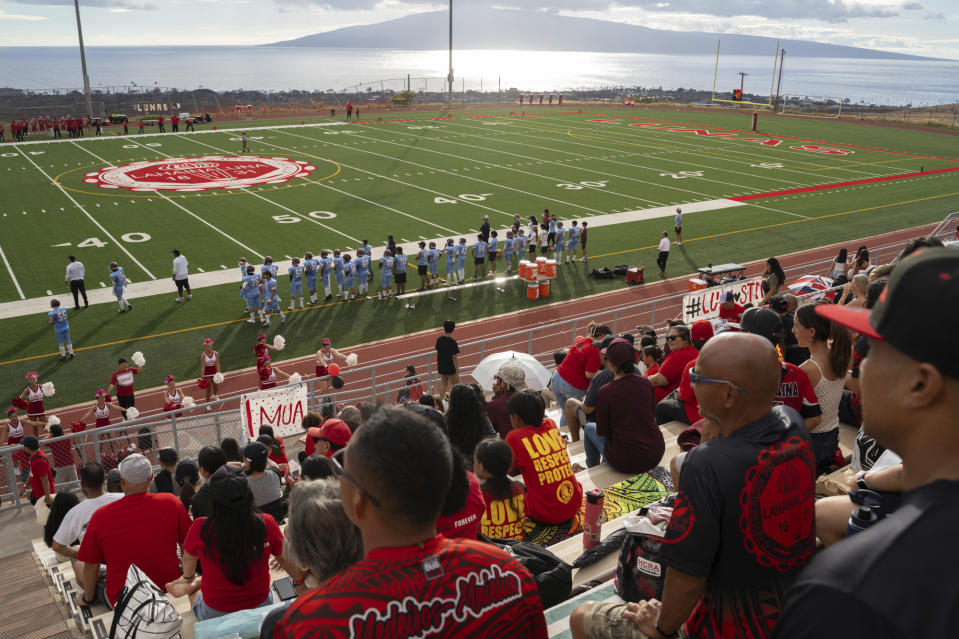 Fans gather for Lahainaluna High School's first home game of the season at Sue D. Cooley Stadium, Saturday, Oct. 21, 2023, in Lahaina, Hawaii. Lahainaluna’s varsity and junior varsity football teams are getting back to normal since the devastating wildfire in August. (AP Photo/Mengshin Lin)