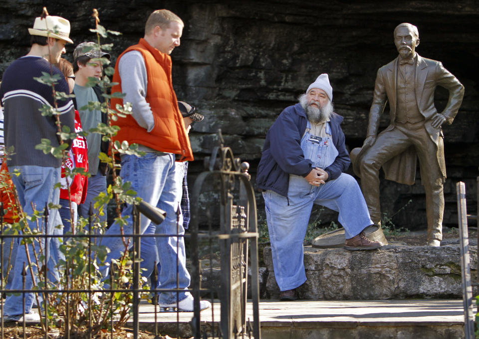 FILE -- This Nov. 27, 2009 file photo shows tour guide David "Porky" Roper, right, resting by a statue of Jack Daniel as he waits for the tour group he is leading to catch up to him at the Jack Daniel's distillery in Lynchburg, Tenn. The 70-mile trip from Nashville to Lynchburg offers a free tour of the oldest registered American distillery. (AP Photo/Mark Humphrey, File)