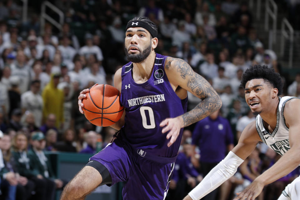 Northwestern's Boo Buie, left, drives against Michigan State's Jaden Akins during the first half of an NCAA college basketball game, Sunday, Dec. 4, 2022, in East Lansing, Mich. (AP Photo/Al Goldis)