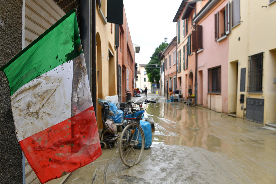 An Italian flag covered in mud flutters on a flooded street in Castel Bolognese. (Reuters)