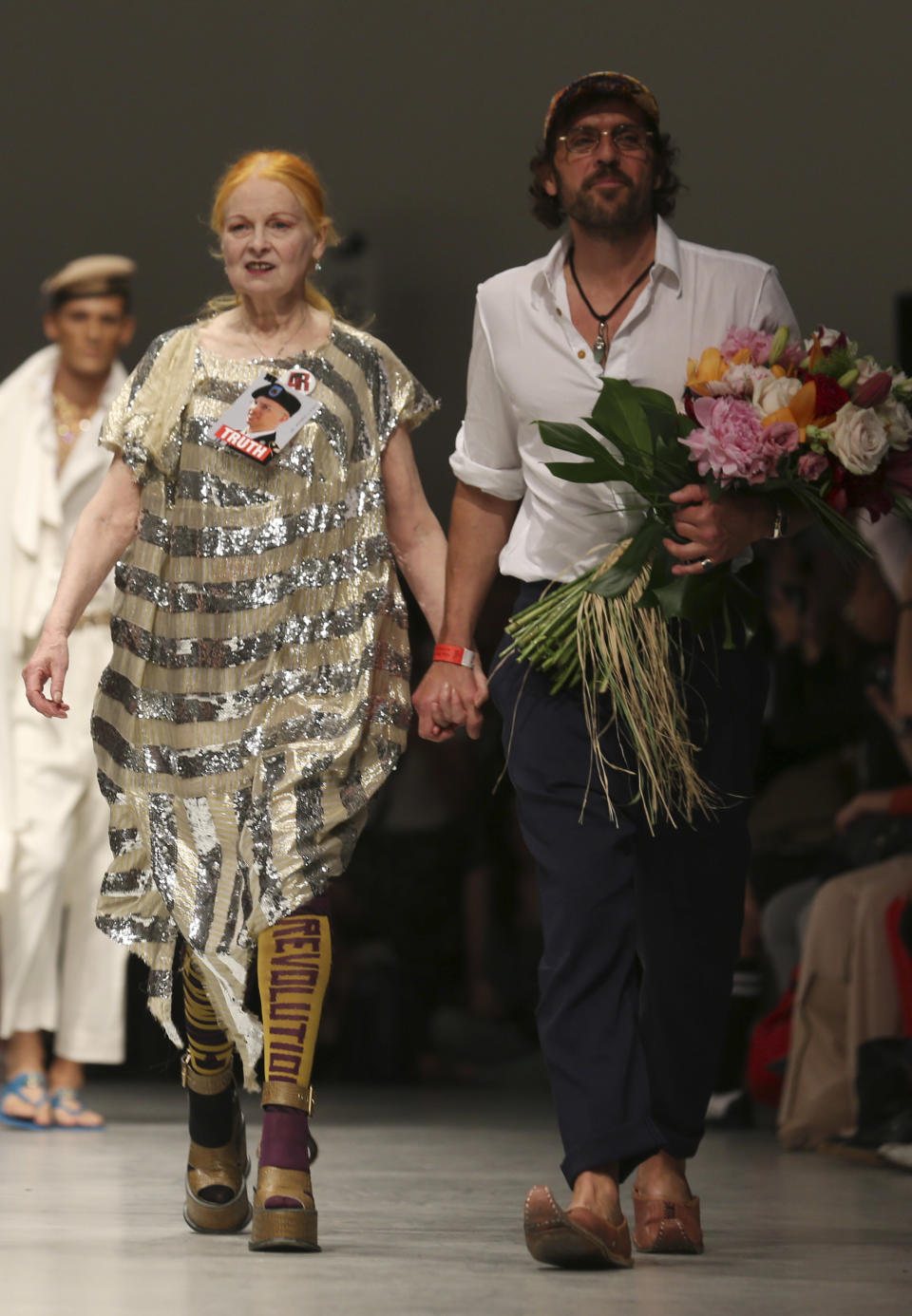 British designer Vivienne Westwood and her husband Andreas Kronthaler walk on the catwalk at the end of the men's Spring-Summer 2014 fashion show, part of the Milan Fashion Week, unveiled in Milan, Italy, Sunday, June 23, 2013. On her dress she pinned a photo of US Army soldier Bradley Manning, who was arrested in 2010 on suspicion of having made public classified material through the website WikiLeaks. (AP Photo/Luca Bruno)