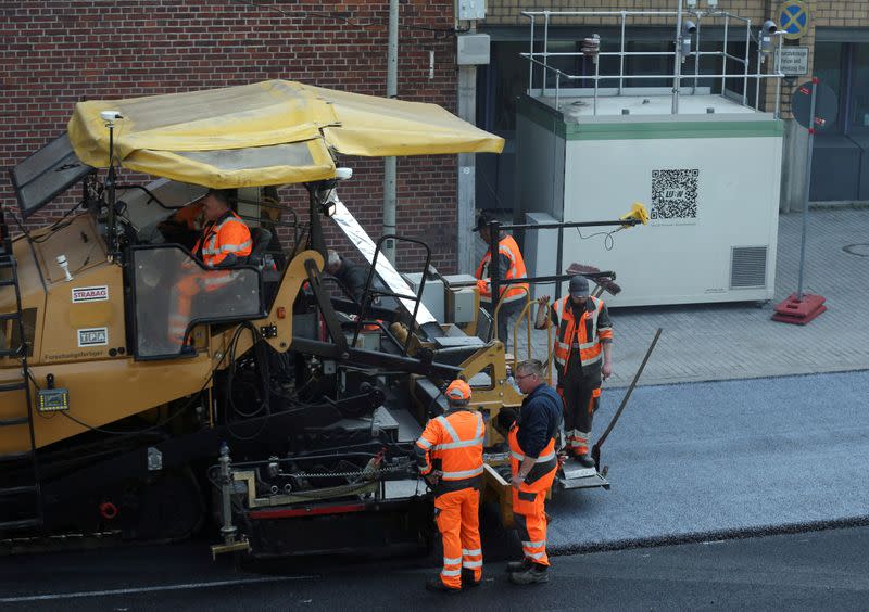 FILE PHOTO: Workers spread asphalt which reduces car emissions at a respirable dust measuring station at Neckartor in Stuttgart