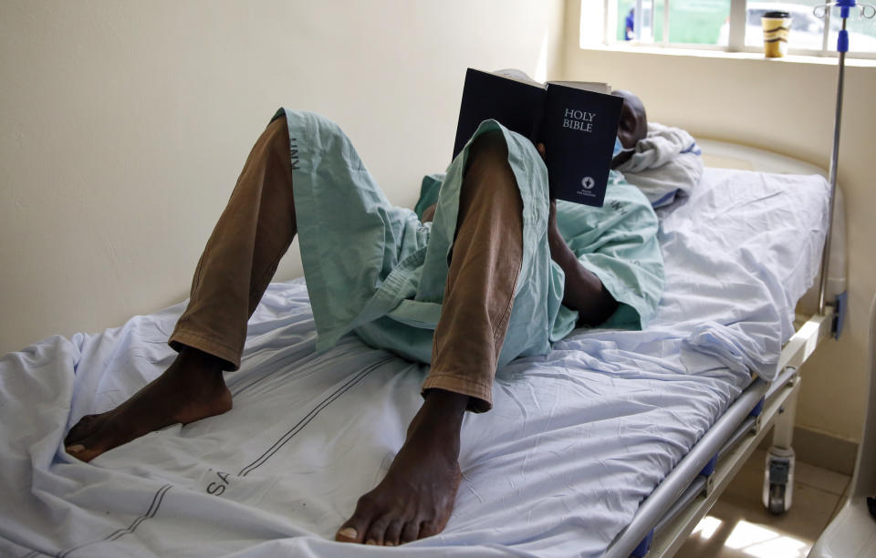 FILE - In this May 1, 2020, file photo, a patient lies on his bed reading the Bible in a ward for those who have tested positive for the new coronavirus, at the infectious disease unit of Kenyatta National Hospital, located at Mbagathi Hospital, in Nairobi, Kenya. A dangerous stigma has sprung up around the coronavirus in Africa — fueled, in part, by severe quarantine rules in some countries as well as insufficient information about the virus. (AP Photo/Brian Inganga, File)