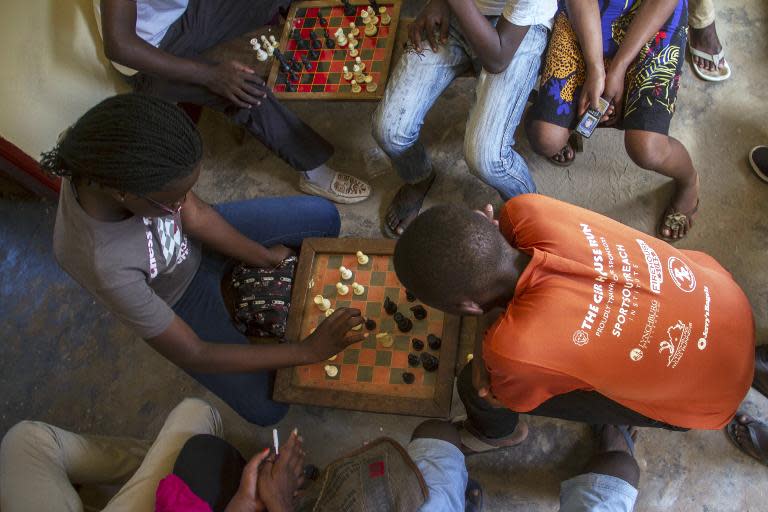 Phiona Mutesi (L) plays a game of chess with her colleagues at the chess academy in Kibuye, Kampala, on January 26, 2015