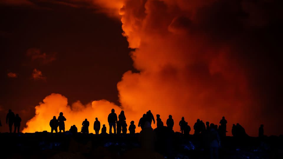 Spectators watch plumes of smoke from volcanic activity between Hagafell and Stóra-Skógfell in Iceland on March 16, 2024. - Marco di Marco/AP