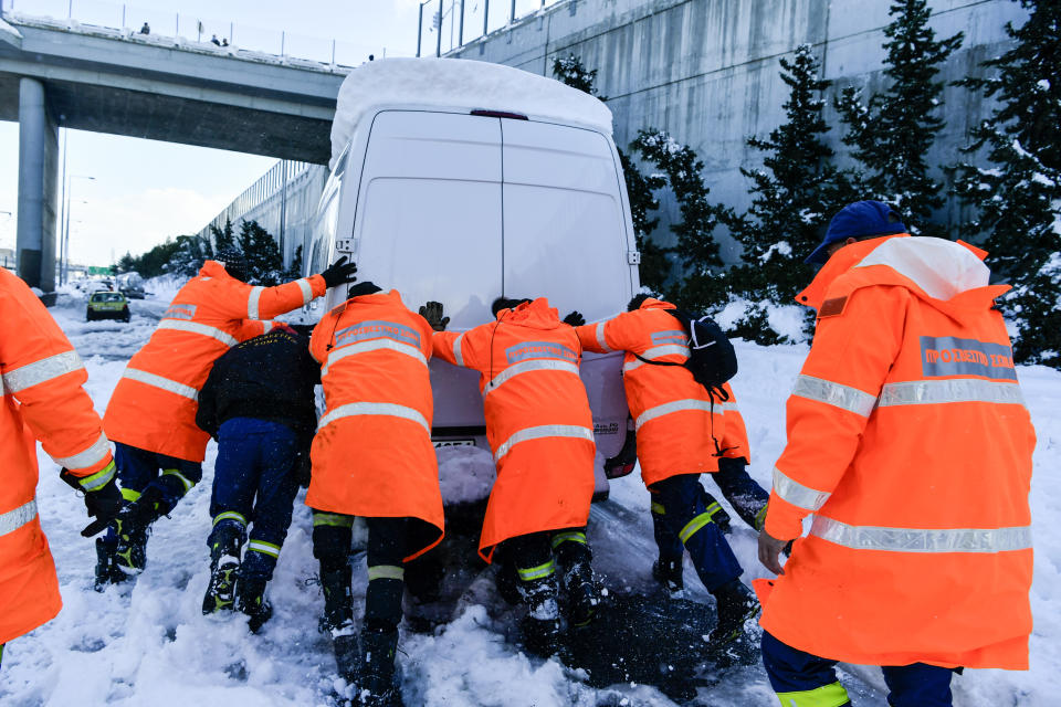 Firemen push a trapped vehicle at a motorway, after a snowstorm, in Athens, on Tuesday, Jan. 25, 2022. Rescue crews in Istanbul and Athens scrambled on Tuesday to clear roads that came to a standstill after a massive cold front and snowstorms hit much of Turkey and Greece, leaving countless people and vehicles in both cities stranded overnight in freezing conditions. (AP Photo/Michael Varaklas)