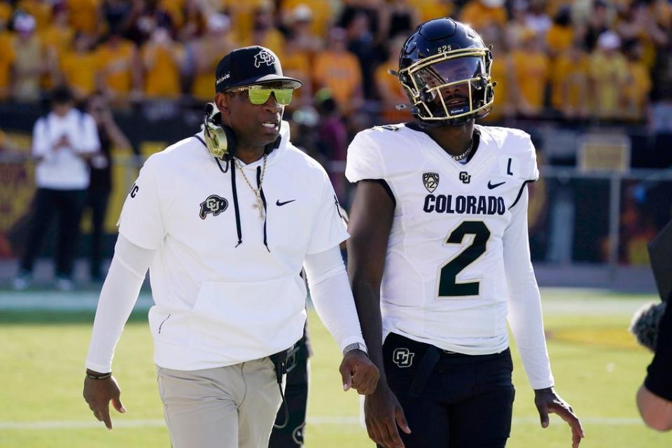 Colorado head coach Deion Sanders, left, talks with his son and starting quarterback Shedeur Sanders (2) prior to an NCAA college football game against Arizona State, Saturday, Oct. 7, 2023, in Tempe, Ariz. (AP Photo/Ross D. Franklin)