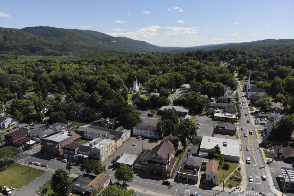 Surrounded by trees and mountains, Ellenville, N.Y., is seen Wednesday, June 16, 2021. Less than 100 miles north of New York City, Ulster County is popular destination for weekenders headed to Woodstock or the Catskill Mountains. Though pretty, there are pockets of poverty. The county is working with the Center for Guaranteed Income Research at the University of Pennsylvania on a pilot program funded by private donations. One hundred households making less than $46,900 a year in May began receiving a $500 payment each month for a year. Recipients of the money can spend it as they wish, but will be asked to participate in periodic surveys about their physical health, mental health and employment status. (AP Photo/Seth Wenig)