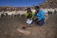 Vilma de Callata, left, and her sister, Katty de Callata, make an offering to the Earth while they look after their animals in Tusaquillas, Jujuy Province, Argentina, Sunday, April 23, 2023. As the world’s most powerful increasingly look toward the lithium triangle, the largest reserve of lithium on earth, as a crucial puzzle piece to save the environment, others worry the search for “white gold” will mean sacrificing that very life force that has sustained the region’s native people for centuries. (AP Photo/Rodrigo Abd)