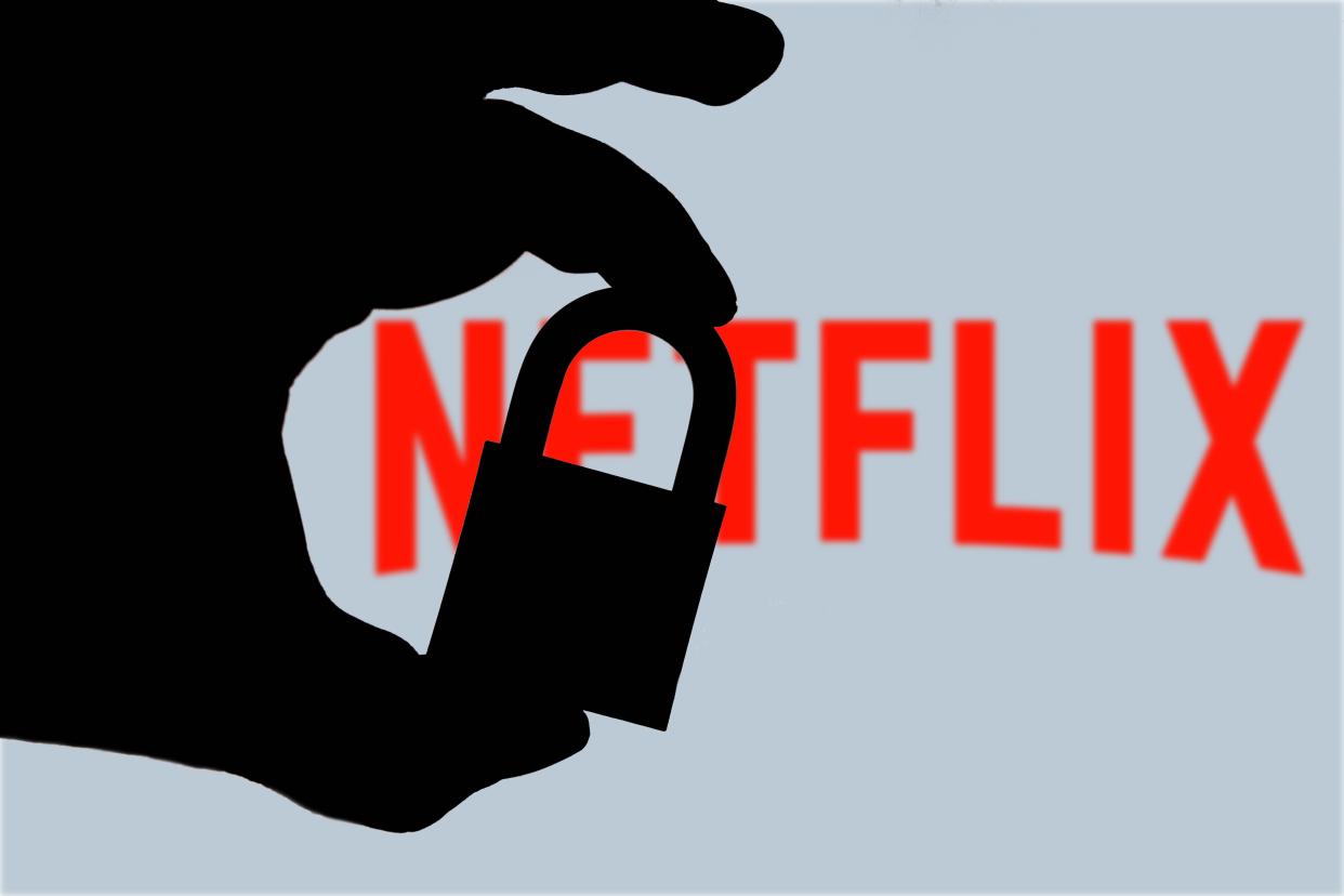 In this photo illustration a hand seen holding a padlock and in the background the logo of Netflix on the computer screen.