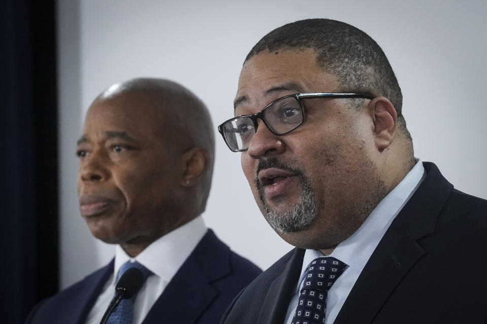 Mayor Eric Adams, left, listens as District Attorney Alvin Bragg, right, speaks during a press conference, where several charges for migrants involved in a Times Square brawl with police, Thursday, Feb. 8, 2024, in New York. (AP Photo/Bebeto Matthews)