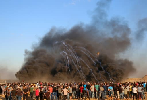 Palestinian protesters watch as tear gas canisters fired by Israeli forces comes through the black smoke of burning tyres during a demonstration on the Israeli border east of Gaza City on September 14, 2018