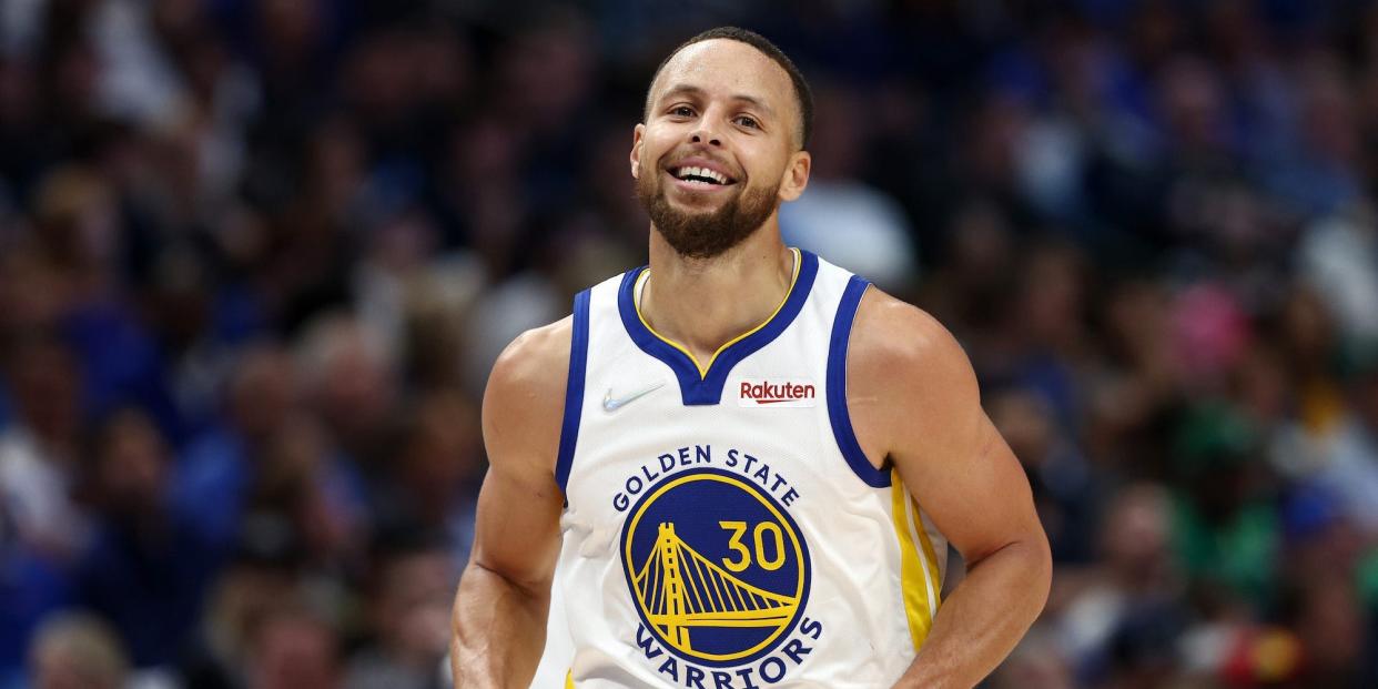 Stephen Curry smiles while running down the court during a game in 2022.