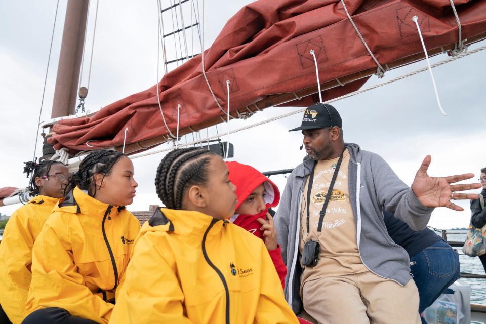 Accent Pontiac Youth participants listen as Jamon Jordan, the official historian of Detroit, participates in the Detroit River Skiff and Schooner program on Aug. 7, 2023, by delivering a history lesson about Detroit and the Detroit River while sailing with the Inland Seas Education Association schooner crew.