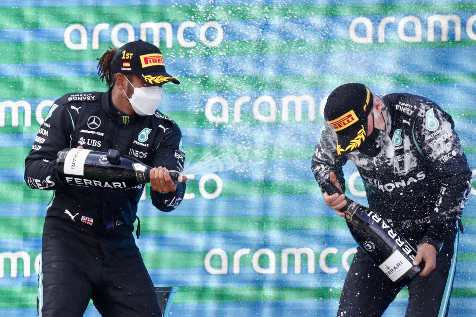 Winner Mercedes driver Lewis Hamilton of Britain, left, celebrates with third placed Mercedes driver Valtteri Bottas of Finland, right, on the podium of the Spanish Formula One Grand Prix at the Barcelona Catalunya racetrack in Montmelo, just outside Barcelona, Spain, Sunday, May 9, 2021. (AP Photo/Joan Monfort)