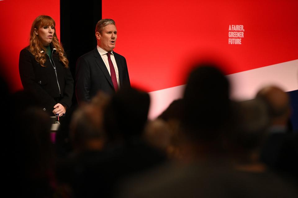 Britain's main opposition Labour Party leader Keir Starmer (R) and Britain's main opposition Labour Party deputy leader Angela Rayner stand with delegates as they sing the National Anthem following a tribute to the late Queen Elizabeth II on the first day of the annual Labour Party conference in Liverpool, north west England on September 25, 2022. (Photo by Paul ELLIS / AFP) (Photo by PAUL ELLIS/AFP via Getty Images)