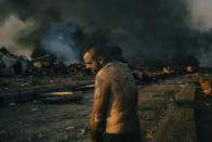 In this image released by World Press Photo, Thursday April 15, 2021, by Lorenzo Tugnoli, Contrasto, for The Washington Post, part of a series titled Port Explosion in Beirut, which won first prize in the Spot News Stories category, shows An injured man stands near the site of a massive explosion in the port of Beirut, Lebanon, while firefighters work to put out the fires that engulfed the warehouses after the explosion, on August 4, 2020. (Lorenzo Tugnoli, Contrasto, for The Washington Post, World Press Photo via AP)