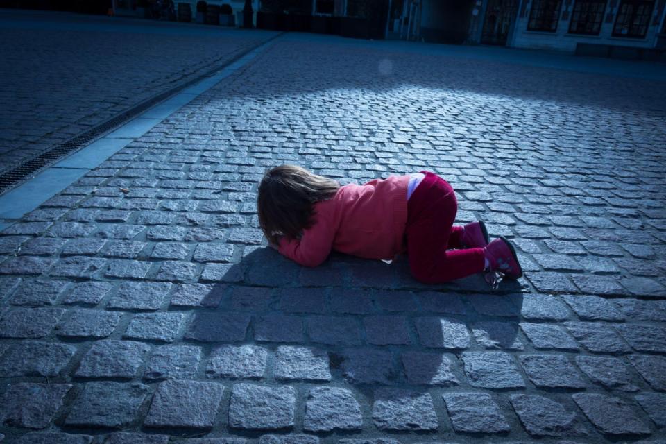 2AYWPWF Child having a tantrum in public, on cobblestone