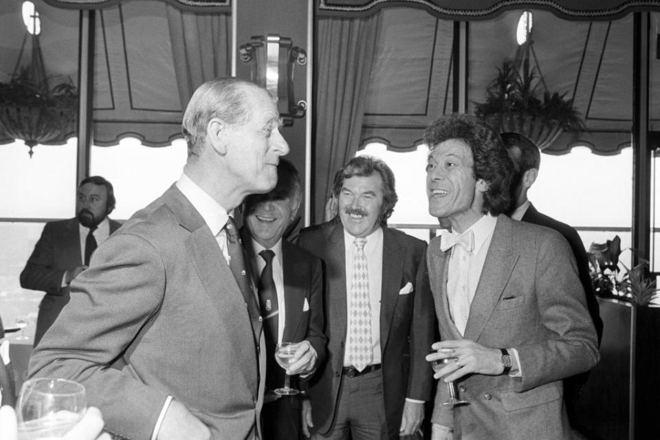 An air of mime at a Variety Club luncheon seemingly enacted by the Duke of Edinburgh (left) and entertainer Lionel Blair (right) of Give Us A Clue TV show, with Dickie Davies (moustache) and actor Sir John Mills (partially hidden) looking on (PA) (PA Archive)