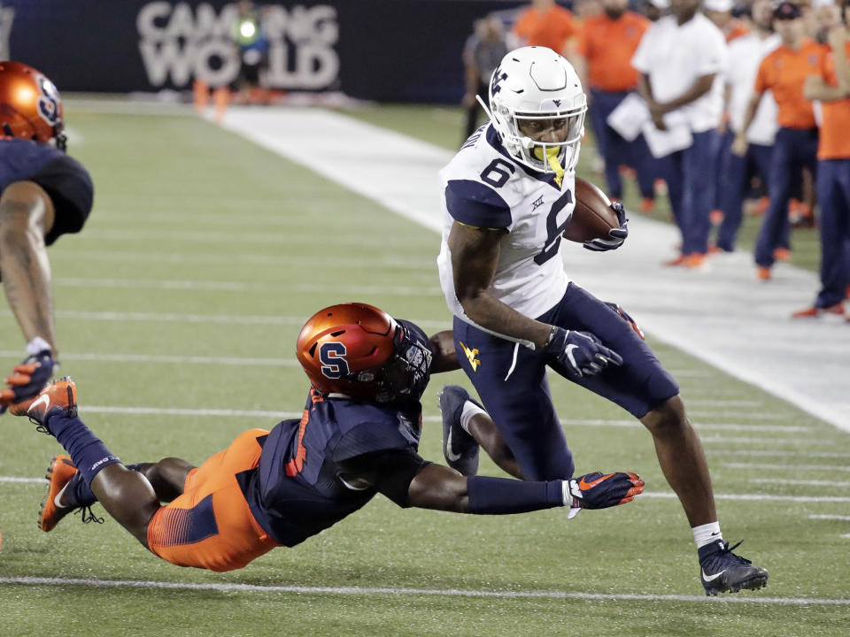 West Virginia running back Kennedy McKoy (6) is tackled by Syracuse defensive back Evan Foster after gaining yardage during the first half of the Camping World Bowl NCAA college football game Friday, Dec. 28, 2018, in Orlando, Fla. (AP Photo/John Raoux)