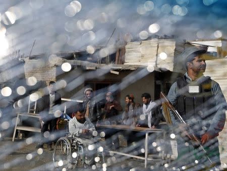 An Afghan police is seen through a cracked window of a vehicle near the site of a suicide attack in Kabul November 27, 2014. REUTERS/Mohammad Ismail