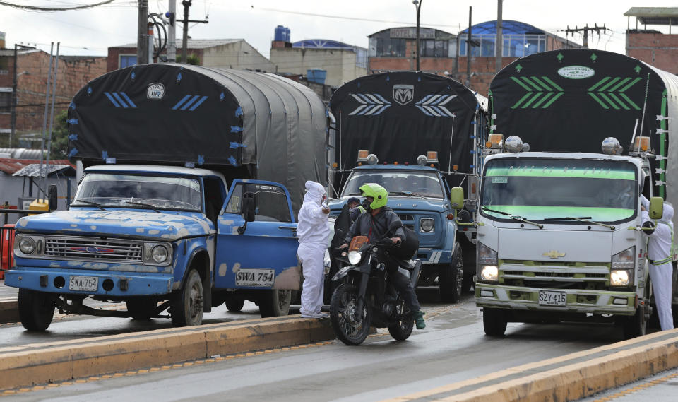 Workers of the Corabastos market, one of Latin America's largest food distribution centers, takes the temperature of drivers due to the presence of the new coronavirus, in the Kennedy area of Bogota, Colombia, Monday, June 1, 2020. Bogota's Mayor Claudia Lopez said Saturday that starting June 1, this working-class area will be under strict quarantine while COVID-19 cases continue to rise. (AP Photo/Fernando Vergara)