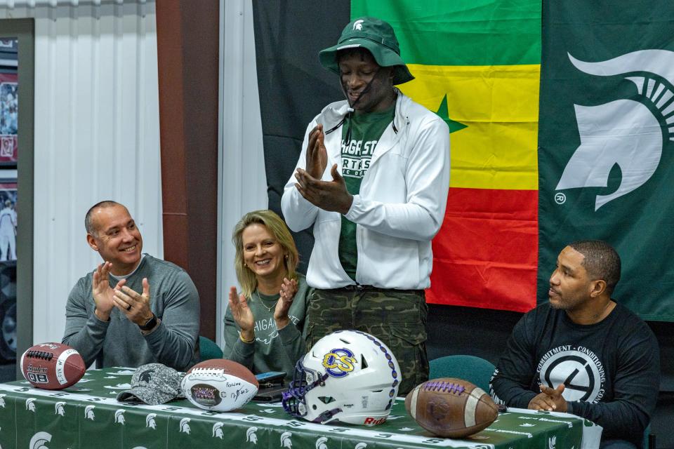 Community Christian's Bai Jobe, center, celebrates after he signs with Michigan State at his home in Norman on Wednesday.